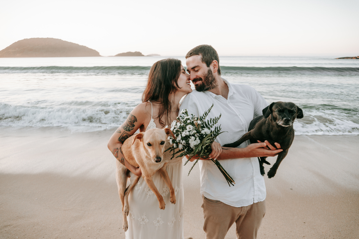 Casal brincando com seu cachorro durante ensaio casal ao ar livre