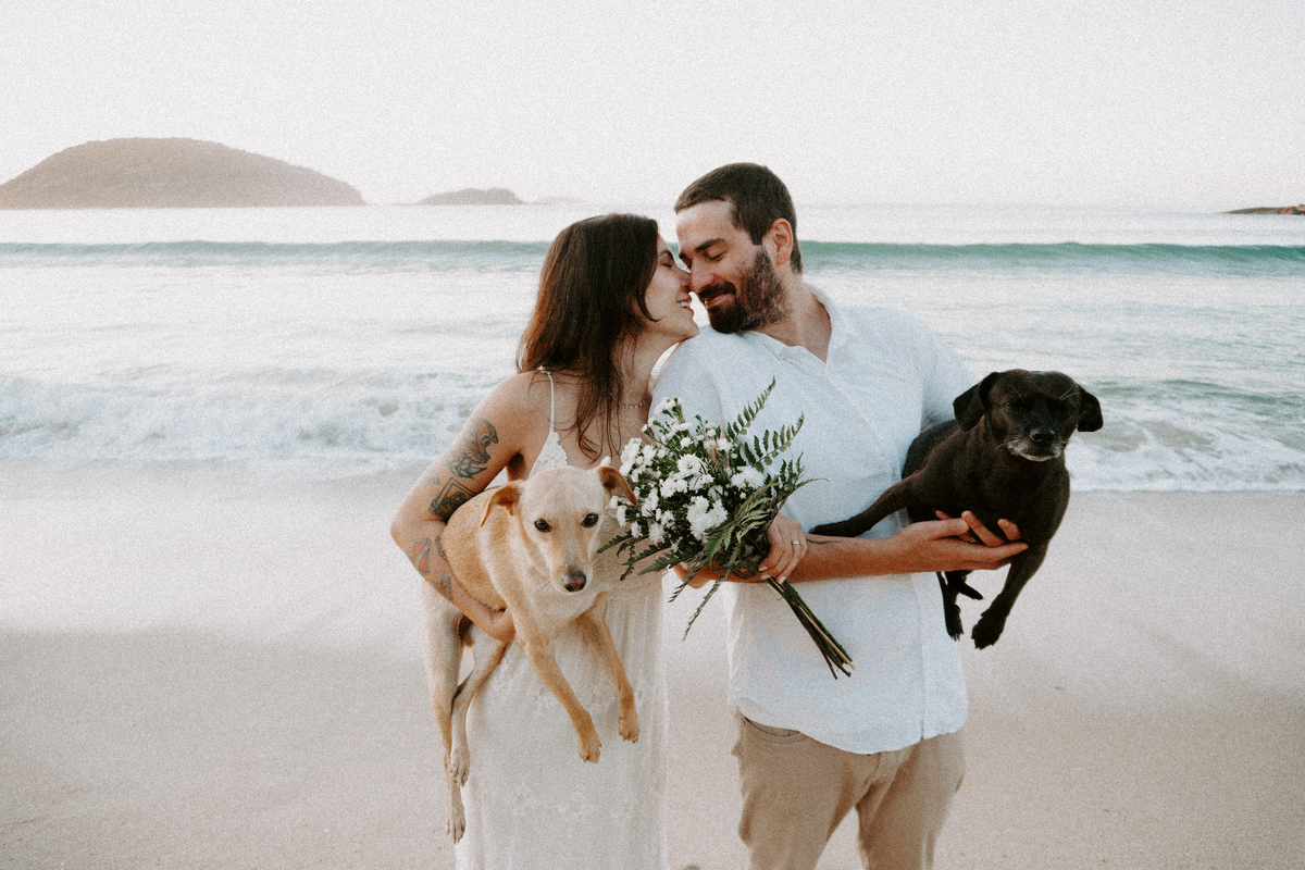 Casal brincando com seu cachorro durante ensaio pré-casamento ao ar livre
