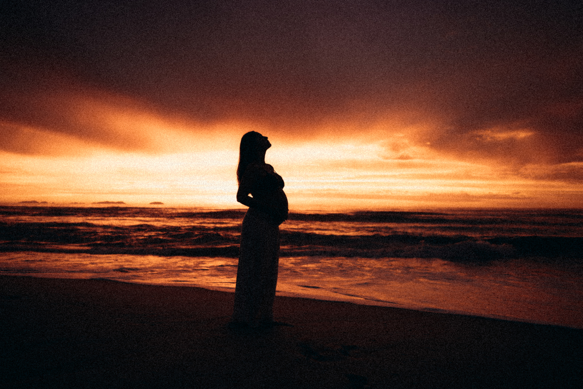 Silhueta de gestante durante ensaio fotográfico ao pôr do sol em Ubatuba.