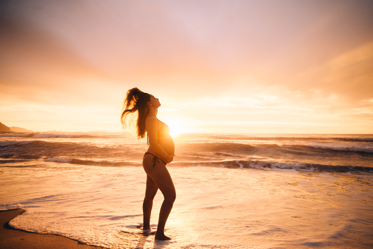 Gestante fotografada na Praia de Itamambuca em Ubatuba durante ensaio gestante ao pôr do sol com luz natural.