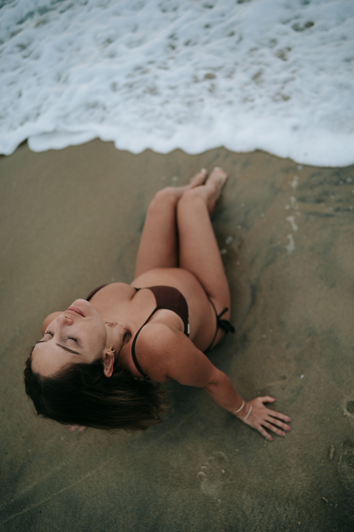 Gestante contemplando o mar durante ensaio fotográfico na praia de Ubatuba.
