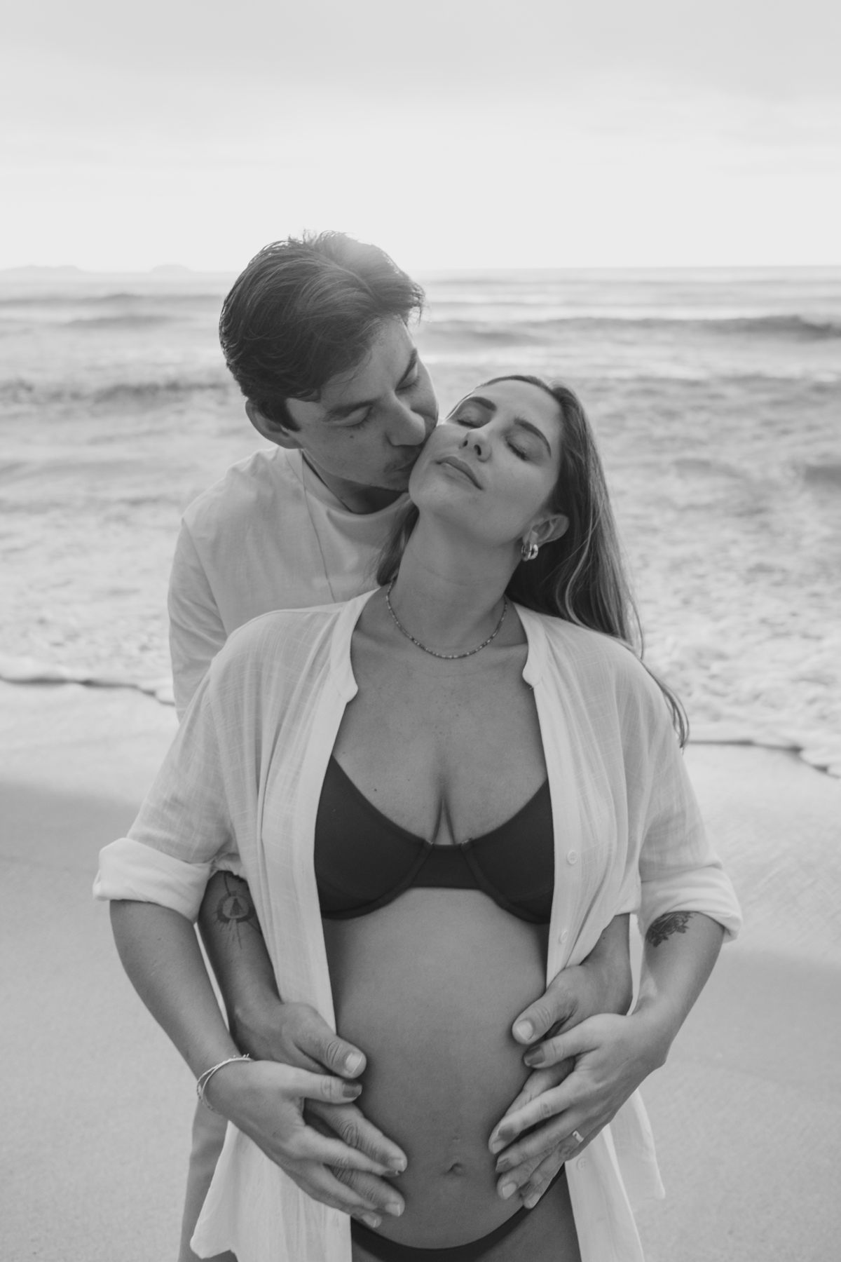 Fotografia de gestante em Ubatuba destacando a barriga durante ensaio na praia.