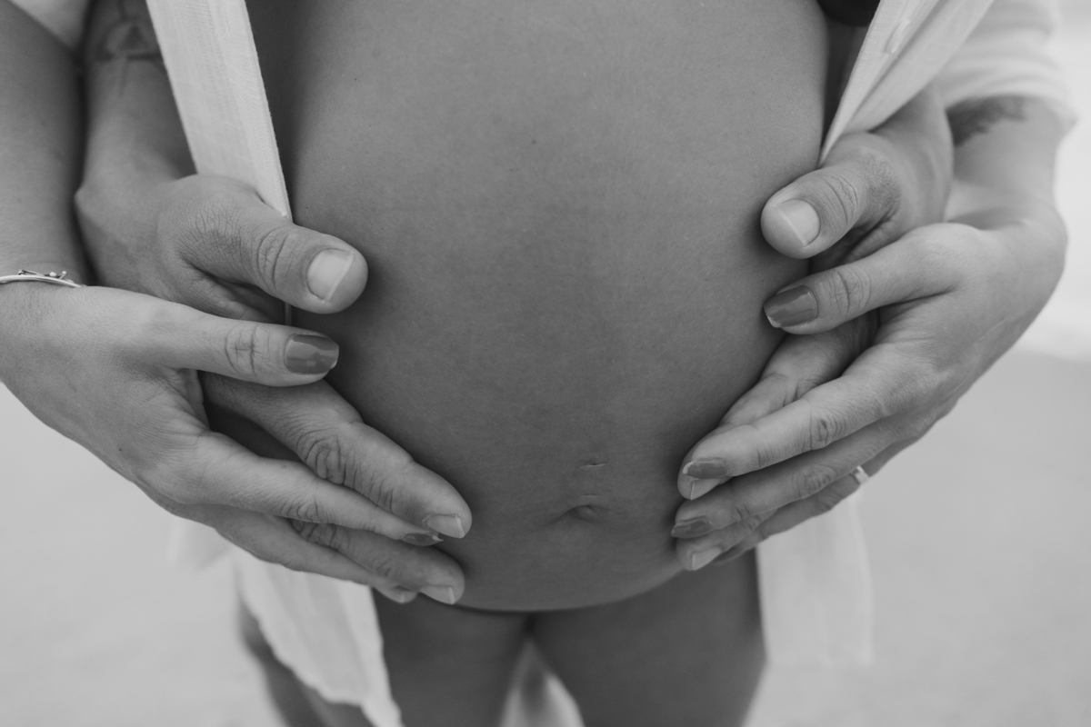 Fotografia de gestante em Ubatuba destacando a barriga durante ensaio na praia.