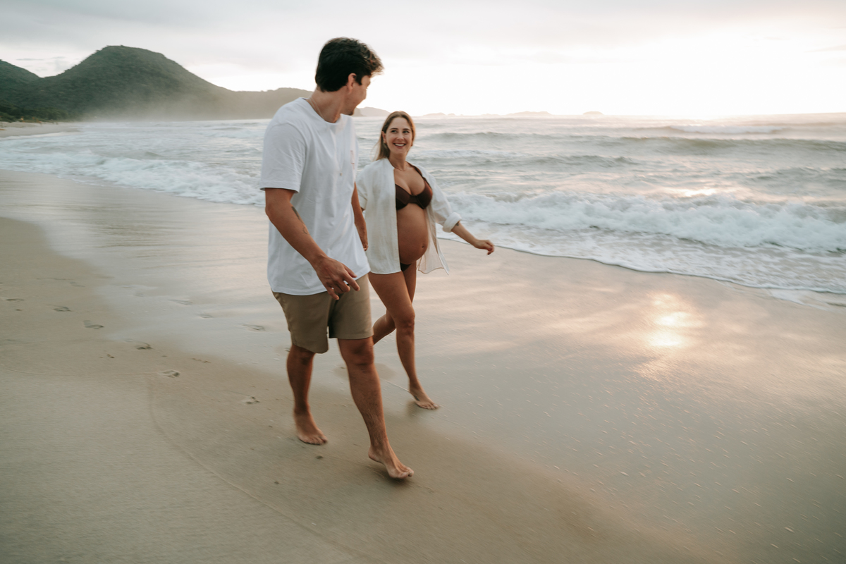 Fotografia de casal esperando o bebê em cenário natural na praia.
