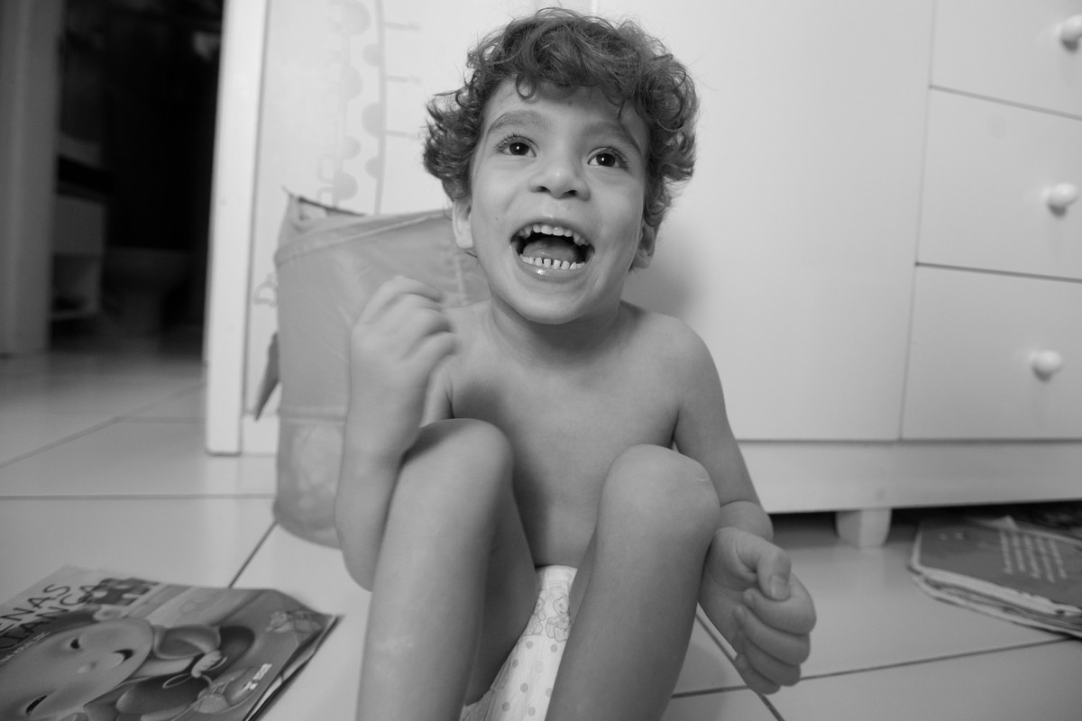 Ícaro sorrindo sentado no chão