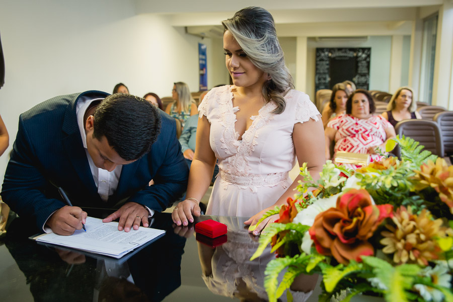 noivo assinando certidão e noiva olhando