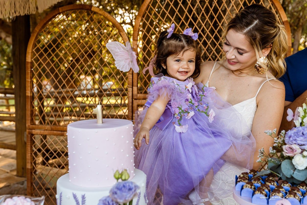 Retrato da Giovana com sua mãe na mesa decorada em sua festa de 1 ano, uma tarde de brincadeiras, afeto e encontros especiais no Complexo Capiba. Fotografia infantil espontânea em Natal, RN.