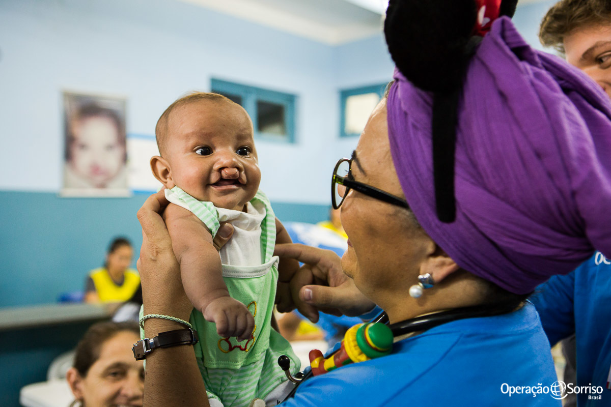 anestesista segurando criança fissura e brincando com ela