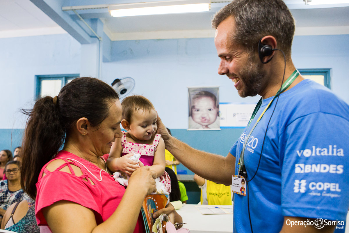 criança fissurada recebendo carinho de voluntario da operação sorriso