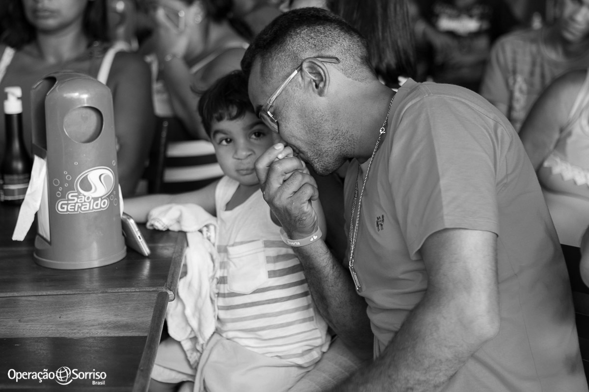 pai fazendo carinho no filho apos descobrir que foram selecionados para cirurgia da Operação Sorriso