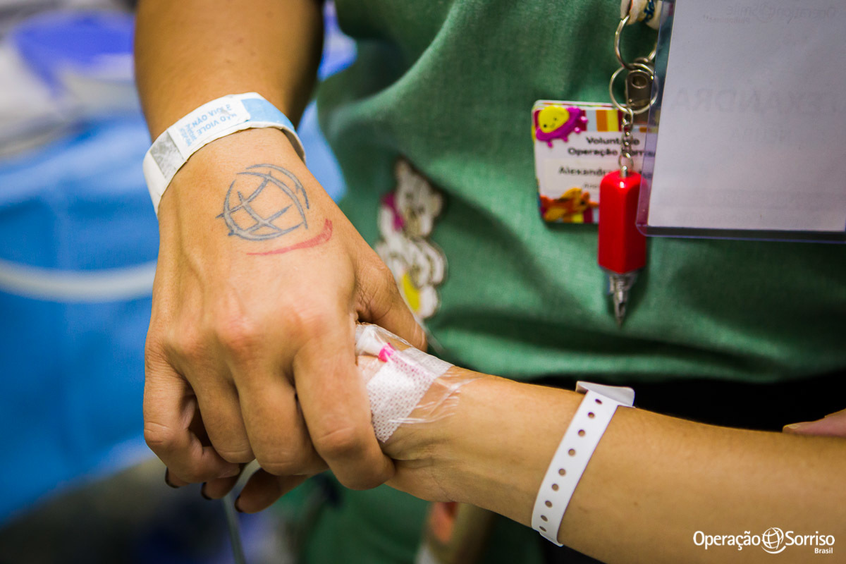 anestesista e voluntaria da Operação Sorriso mostrando a sua tatuagem com logo da ONG