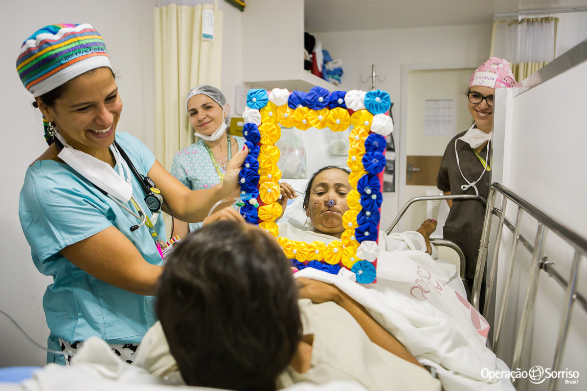 voluntaria da operação sorriso segura espelho para que paciente possa se ver pela primeira apos a cirurgia