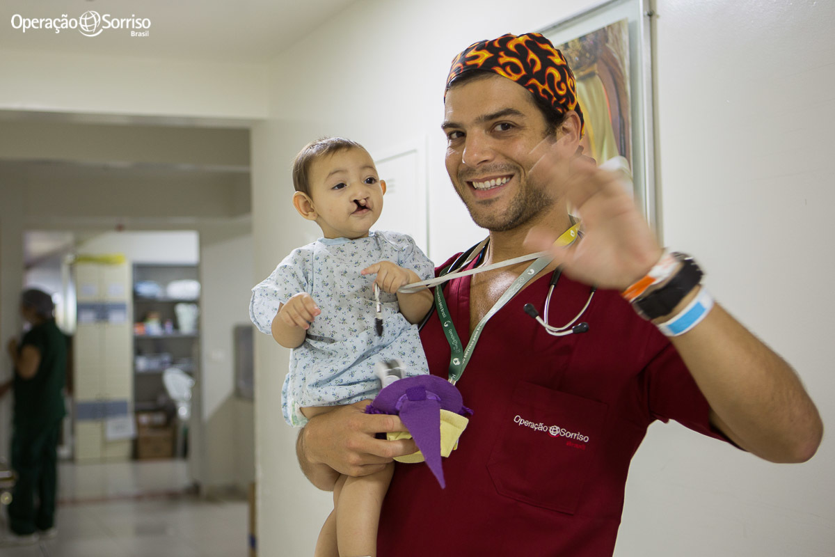 anestesista com bebe no colo entrando no centro cirurgico e dando tchau para a mãe