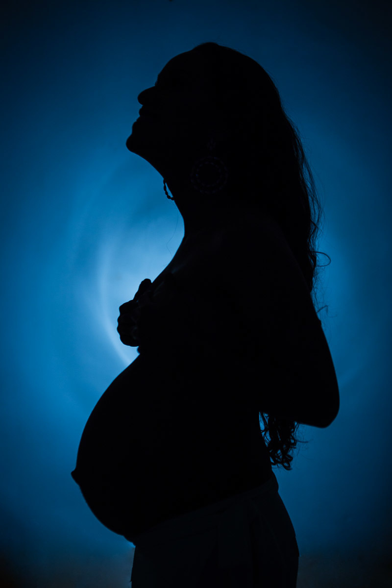 fundo azul com silhueta de gestante segurando os seios e olhando pra cima