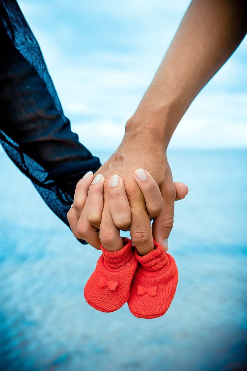 maos de pais segurando o sapatinho do bebe