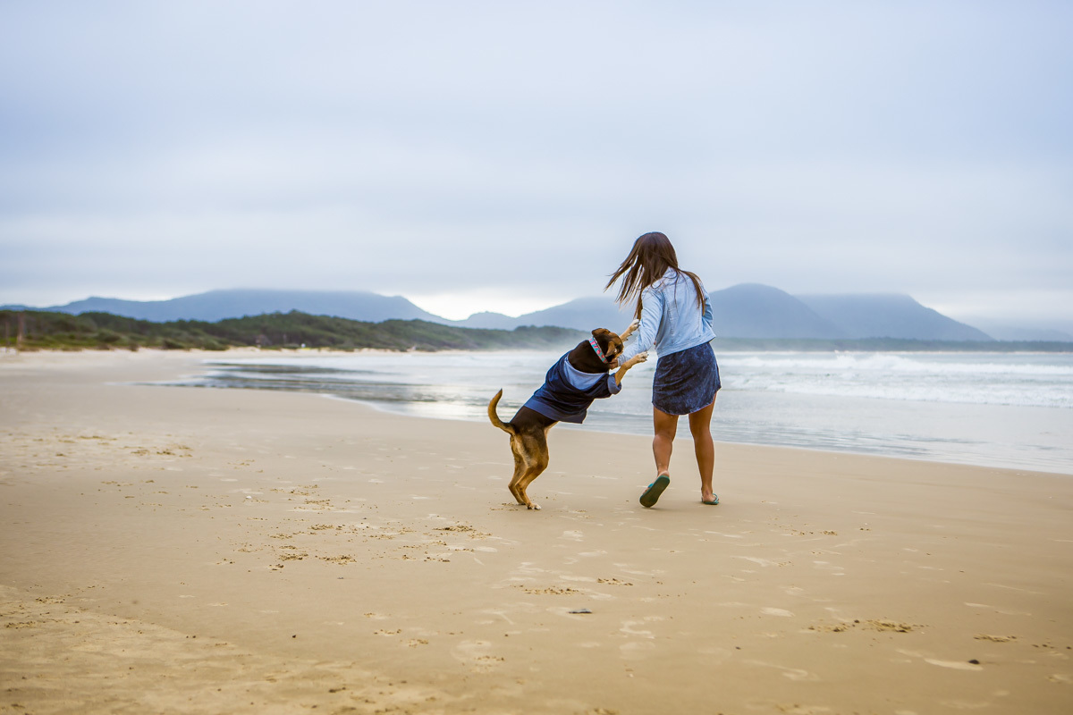 cachorra brincando com mulher na praia