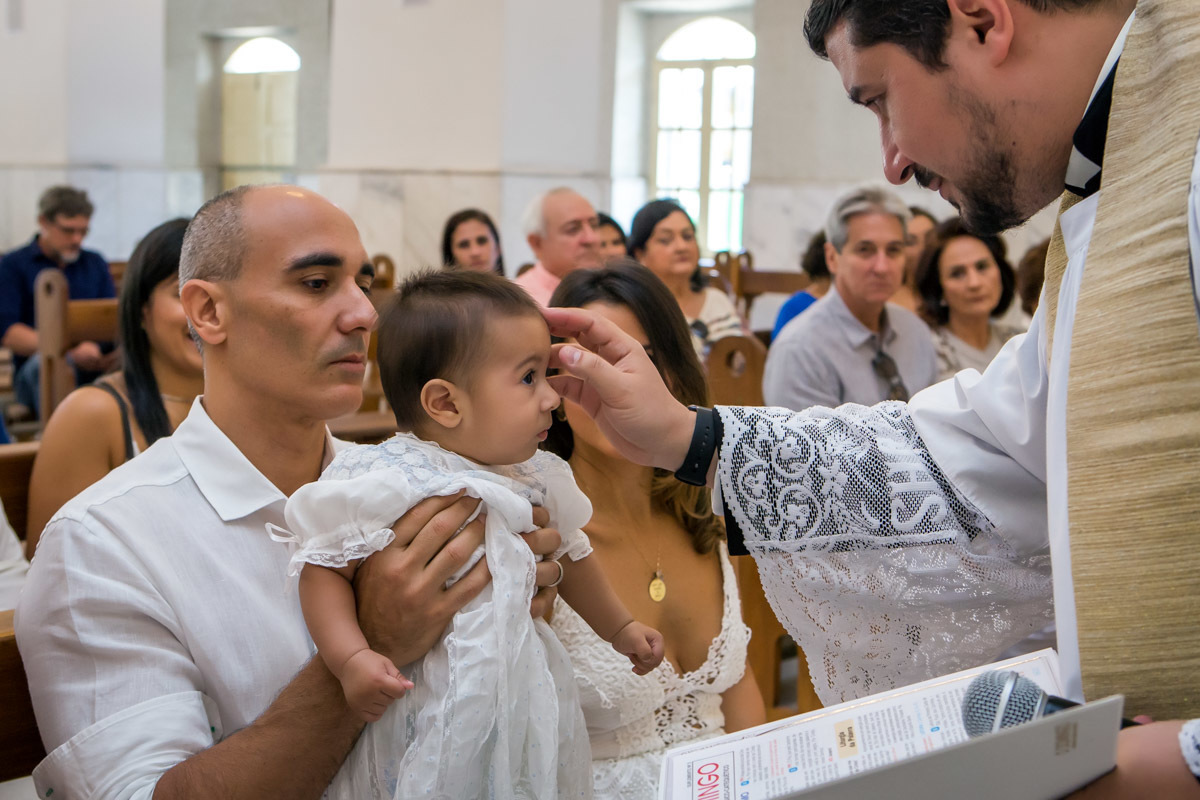 padre faz sinal da cruz na testa de criança