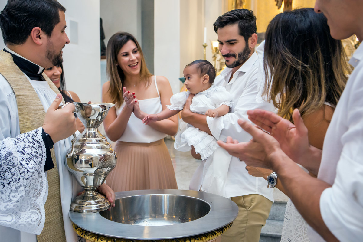 padrinhos e pais ao redor da pia batismal batem palmas