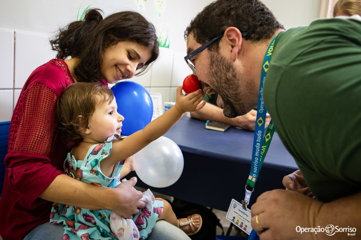 voluntario com nariz de palhaço brincando com menina