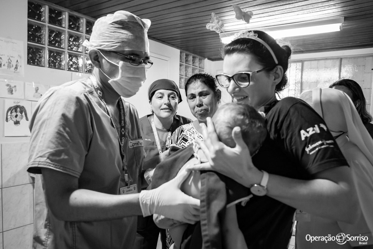 psicologa entregando criança a anestesista enquanto a mãe observa chorando