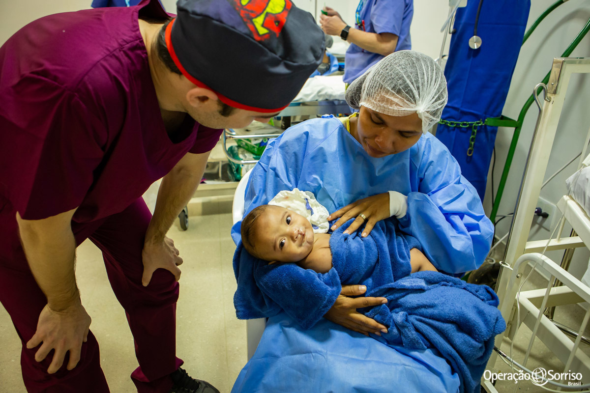 mãe abraçada com filho após a cirurgia e médico conversando com a criança
