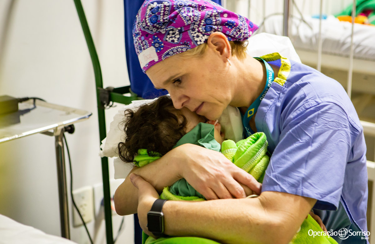 enfermeira abraçada com criança pós cirurgia