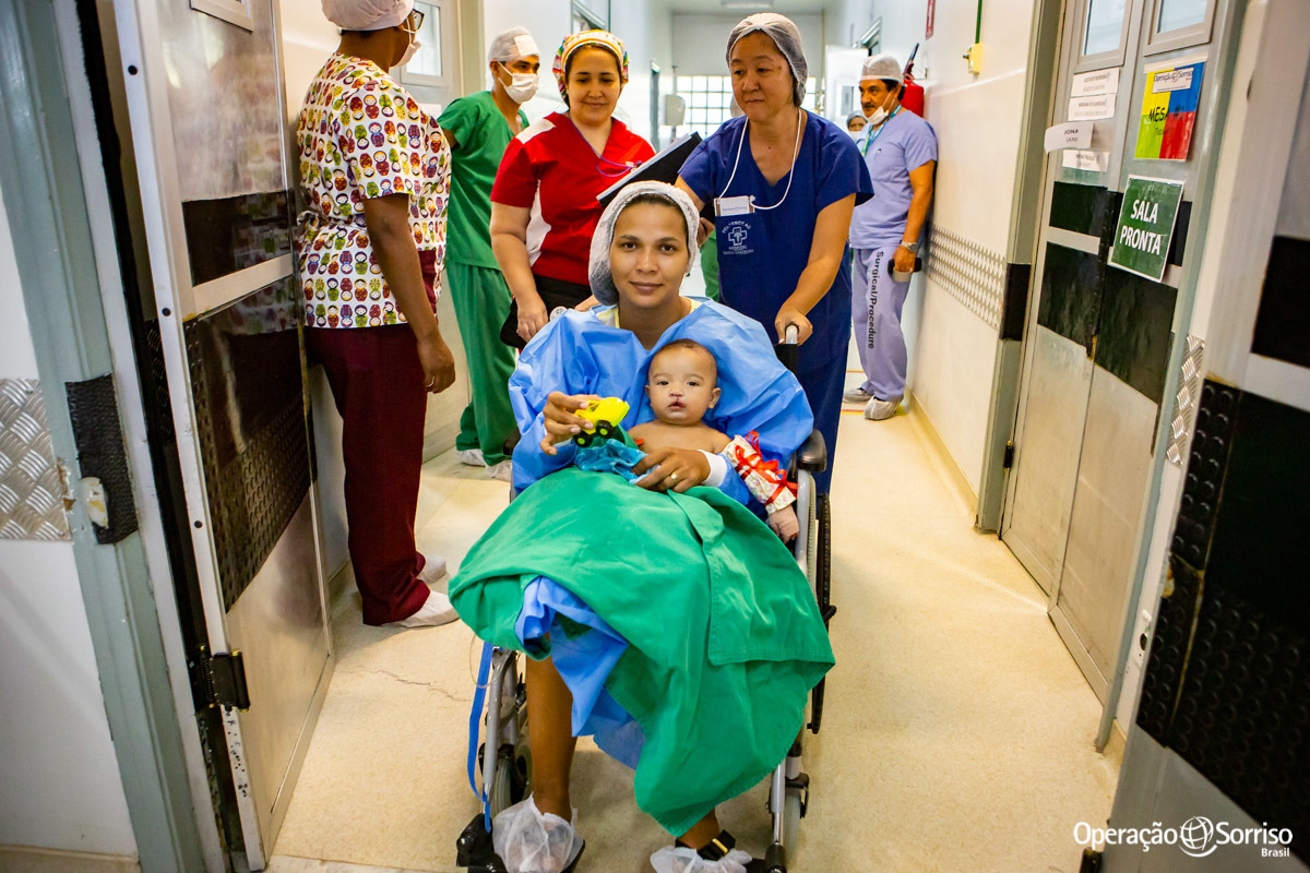 mãe em cadeira de rodas saindo do centro cirúrgico com filho após a cirurgia