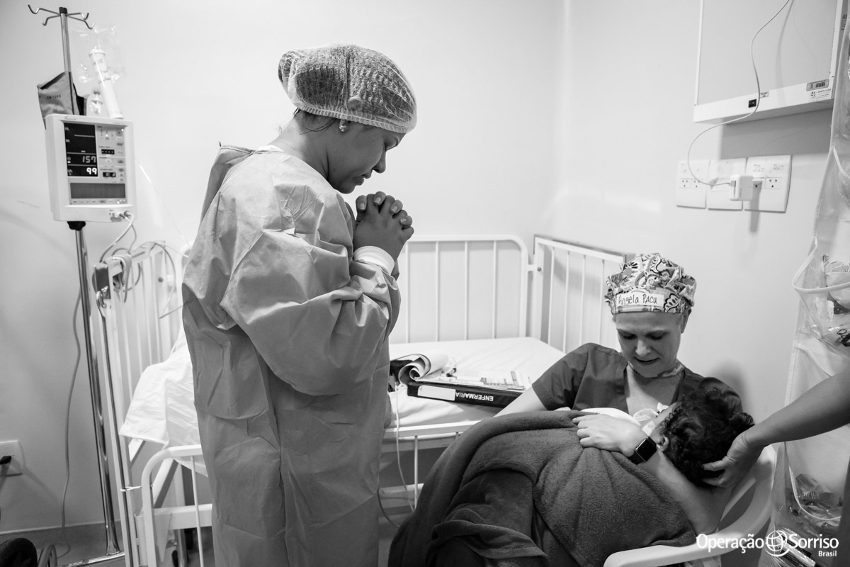 mãe com mãos cruzadas rezando ao ver ilho após a cirurgia