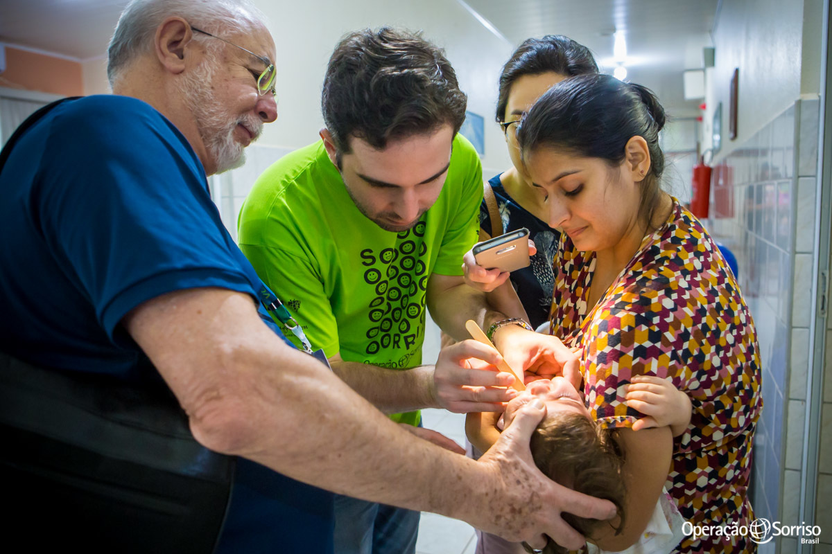 médicos olhando boca de criança um dia após a cirurgia