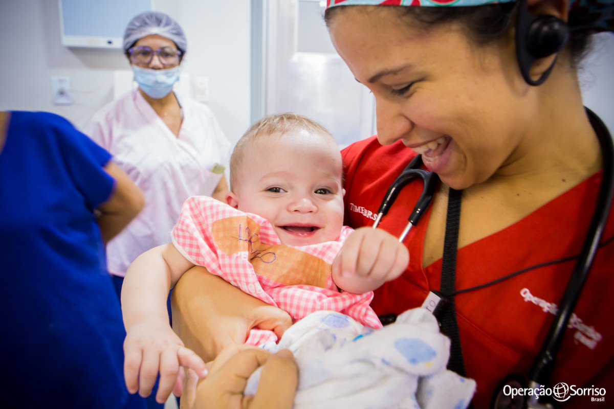 criança no colo da médica e sorrindo