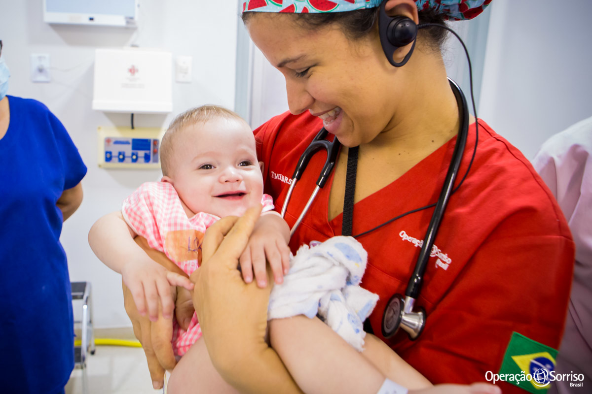 criança no colo da médica e sorrindo
