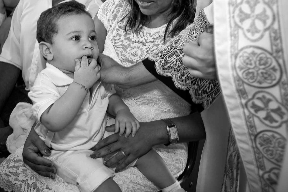 criança olhando para a o padre enquanto ele faz sinal da cruz em seu peito