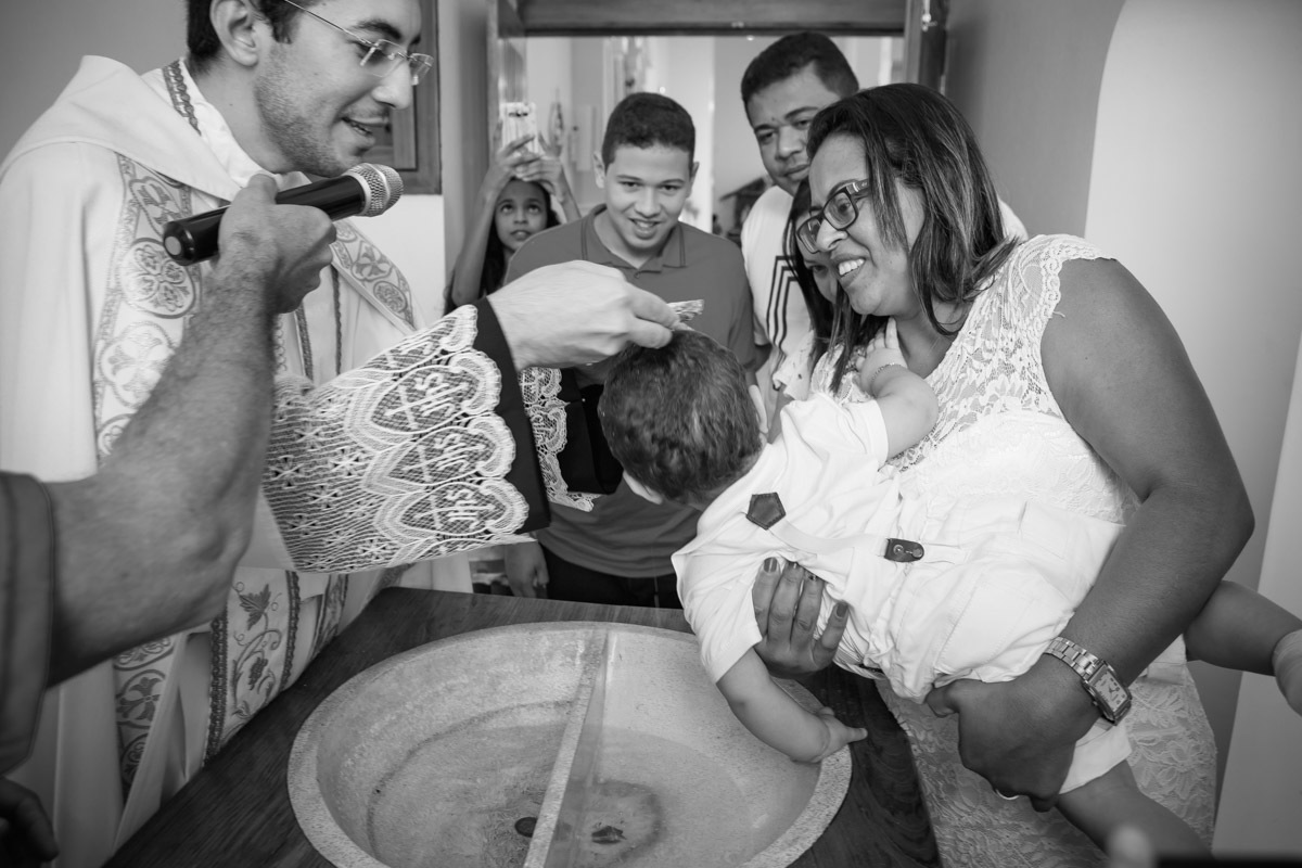 criança querendo sair da pia batismal