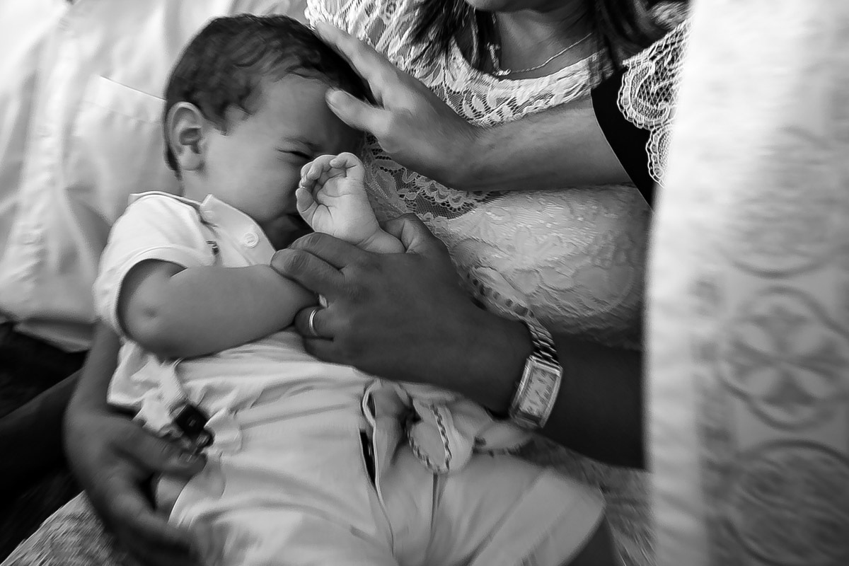 criança se esquivando do padre quando ele faz sinal da cruz na sua testa