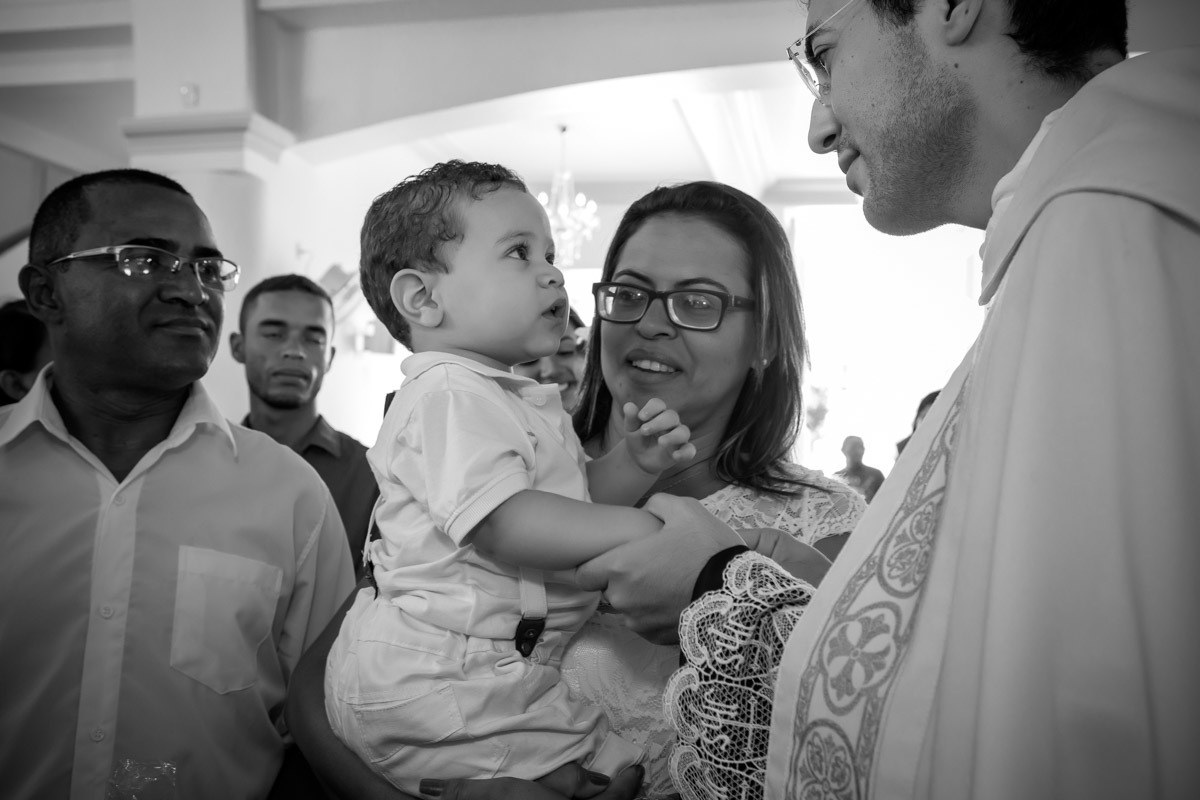 criança olhando para o padre que segura sua mão