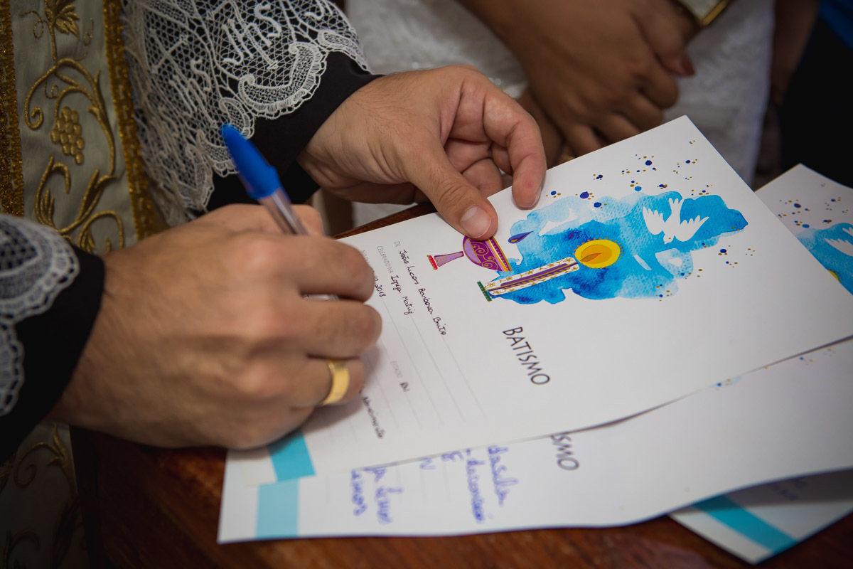 padre assinando o certificado de batismo