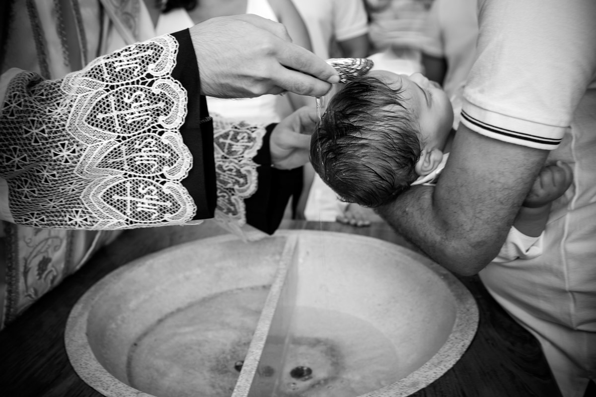 padre batizando criança colocando agua em sua cabeça