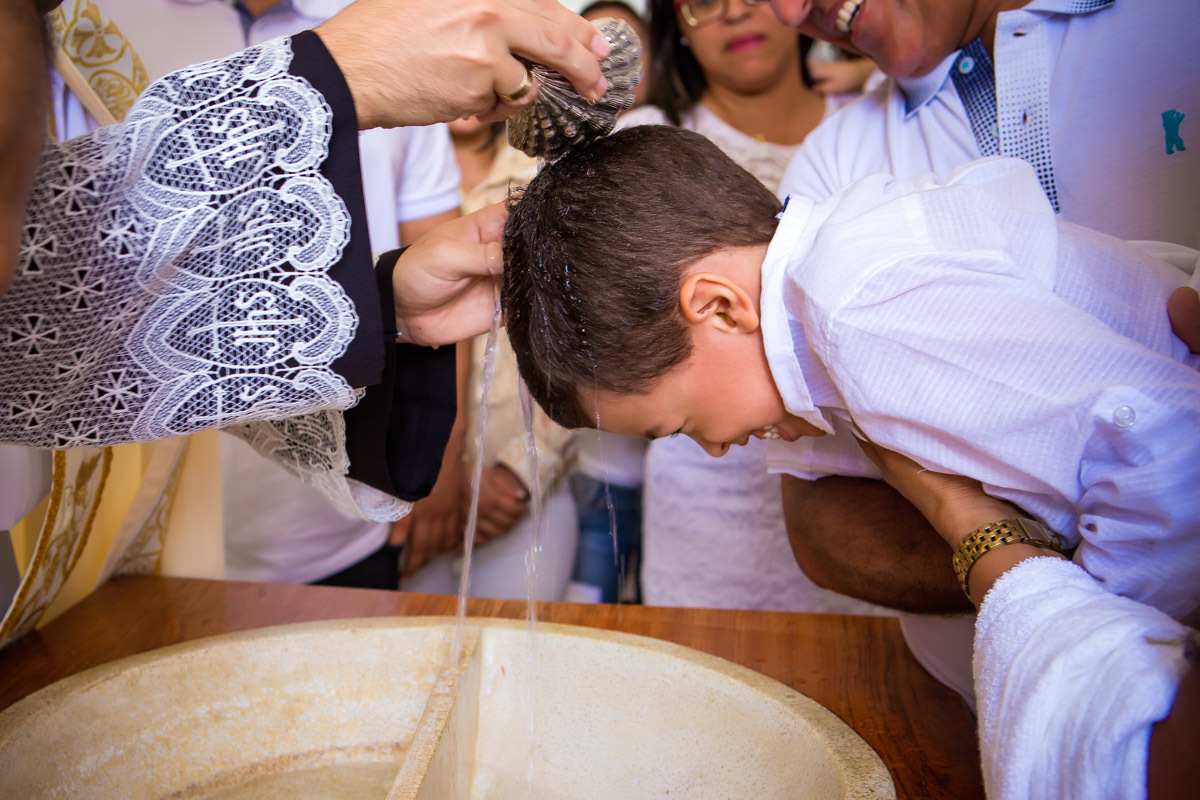 padre batizando criança colocando agua em sua cabeça