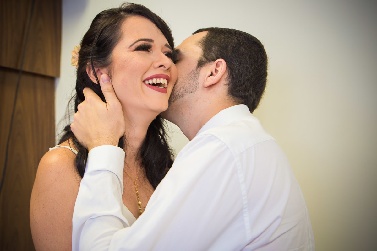 Noivos falando no ouvido na noiva que sorri apos o casamento no Cartorio de Parnamirim