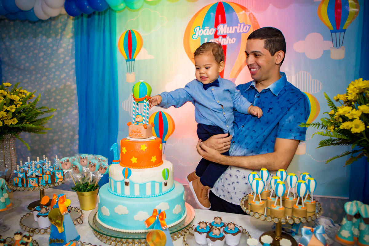 bebe brincando com topo do bolo no colo do tio no aniversário ursinho baloeiro