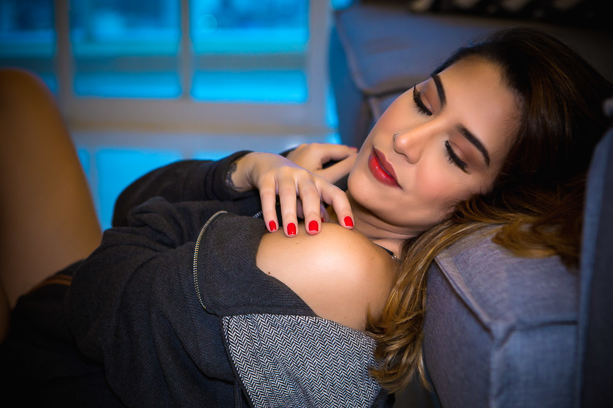 mulher sentada no chão encostada no sofá se abraçando