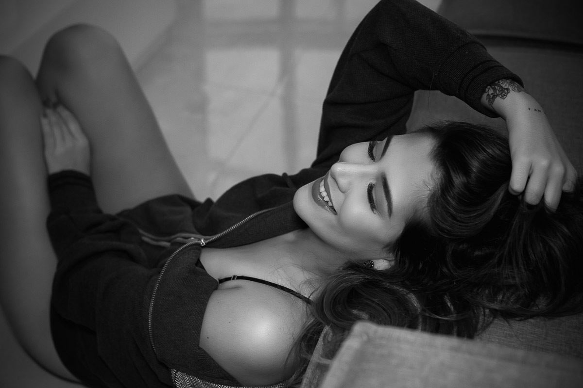 mulher sentada no chão encostada no sofá com mão no cabelo