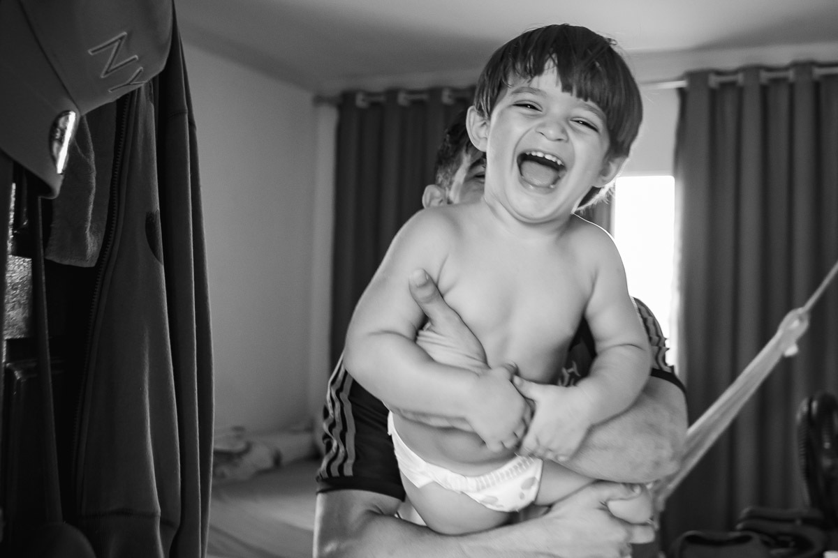 criança no colo do pai rindo