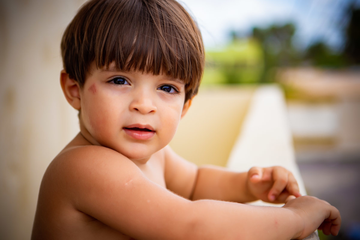 criança encostada no muro olhando para a rua