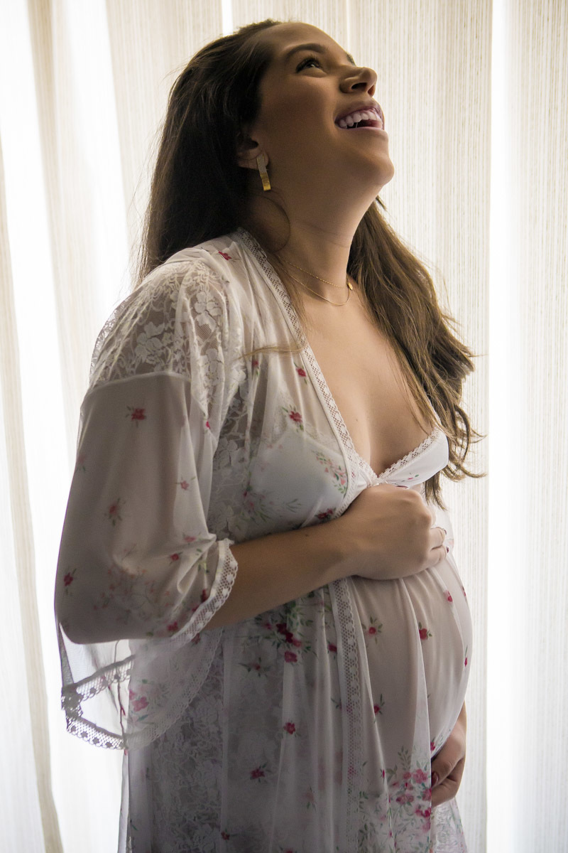 Gestante de camisola segurando barriga no quarto