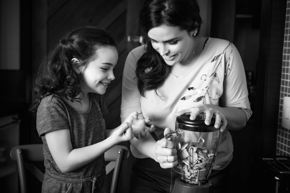 filha rindo enquanto ajuda mãe a triturar biscoitos
