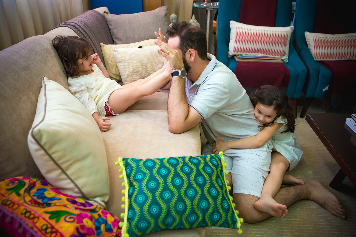 irmãs brincando no sofá e no chão com o pai