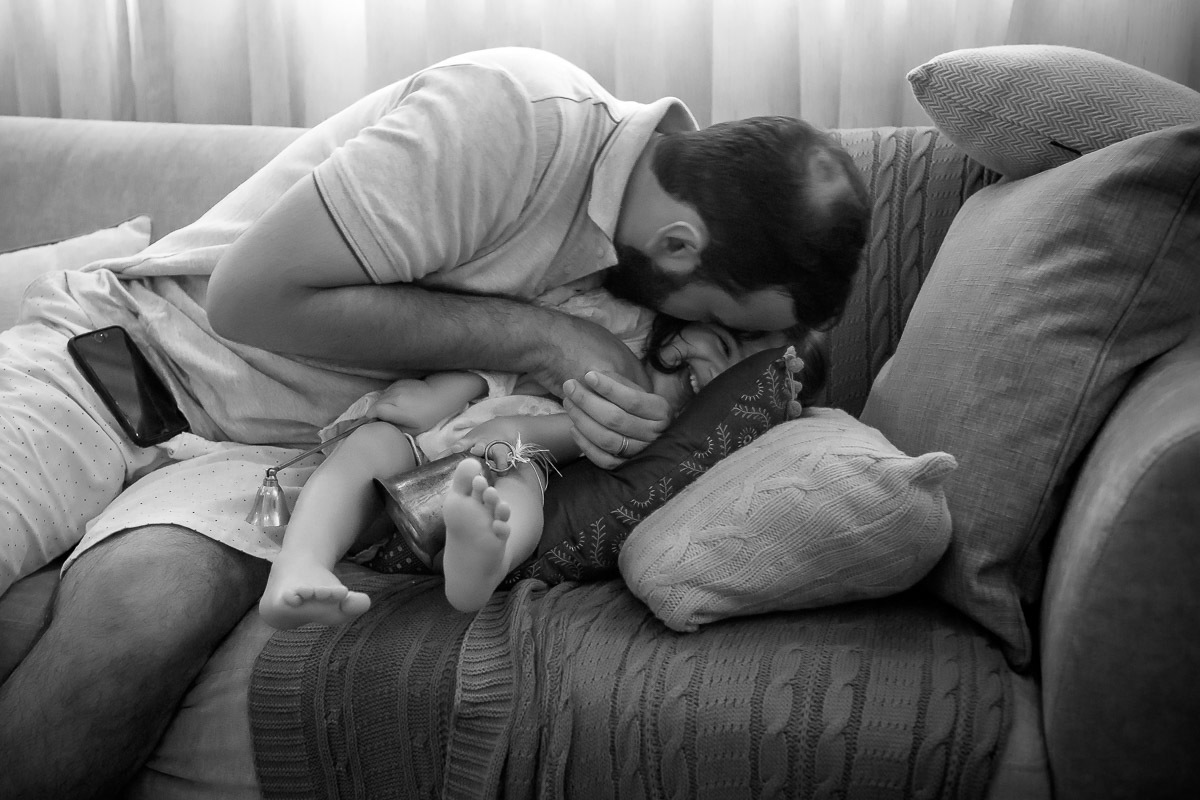 pai fazendo cocegas na filhas mais nova no sofá