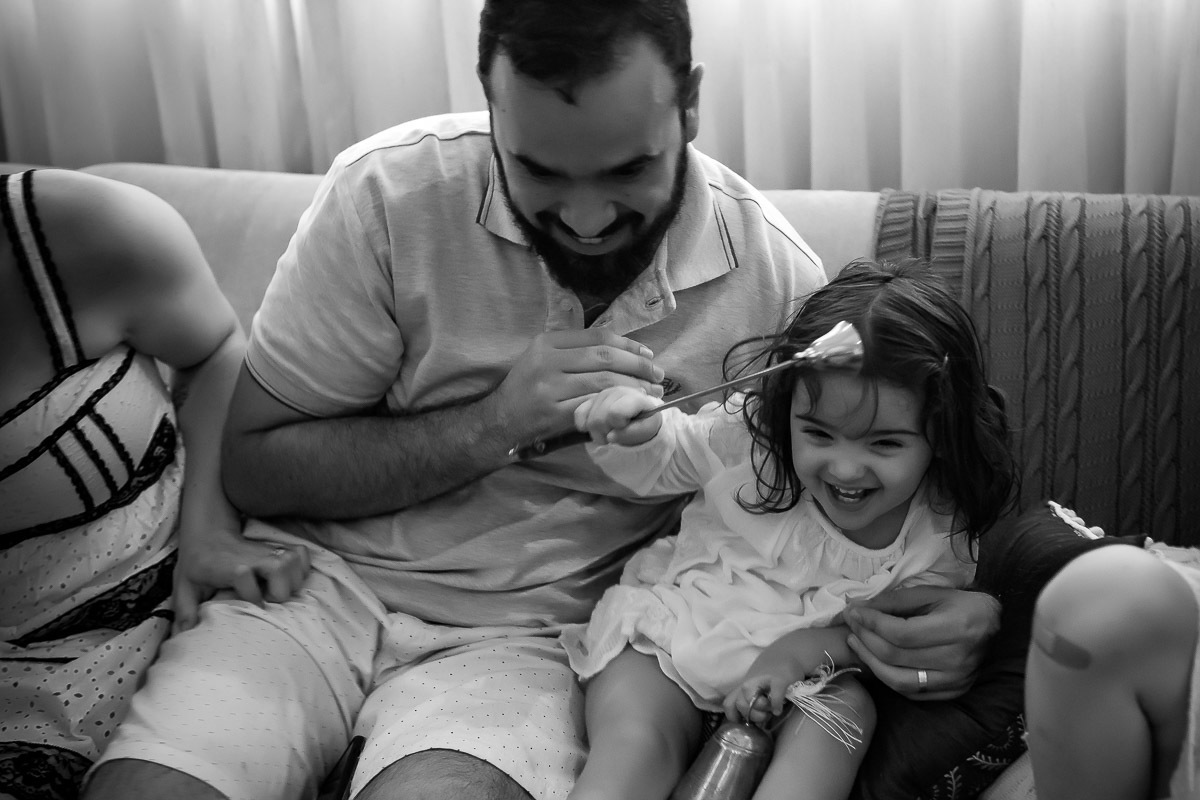 pai fazendo cocegas na filhas mais nova no sofá