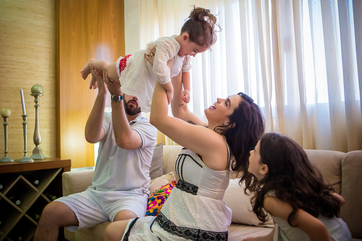 mãe e pai fazendo aviãozinho com filha